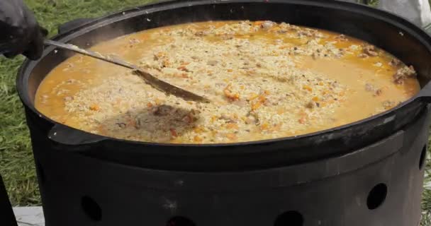 Cook está misturando pilaf e segurando colher de cozinha — Vídeo de Stock