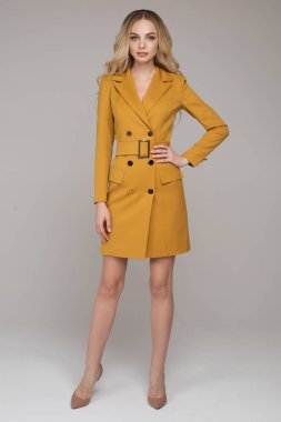 Beyaz stüdyo arka planında izole edilmiş şık elbiseli çekici genç sarışın manken.