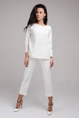 Kameraya bakarak saçlarına dokunan sıradan esmer kadının portresi.