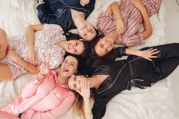 Top view relajantes amigas jóvenes tumbadas en la cama divirtiéndose posando juntas — Foto de Stock