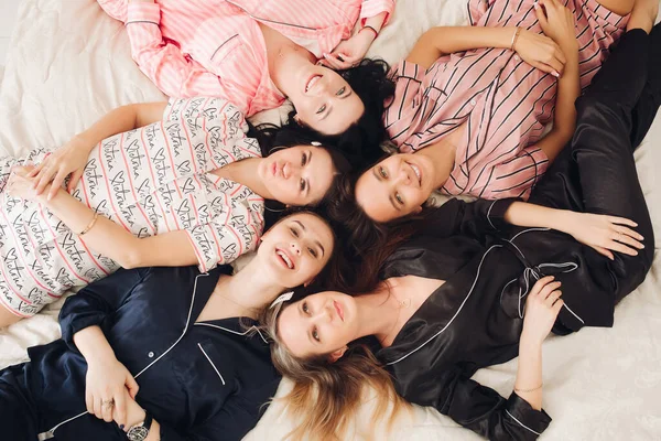 Top view relajantes amigas jóvenes tumbadas en la cama divirtiéndose posando juntas — Foto de Stock