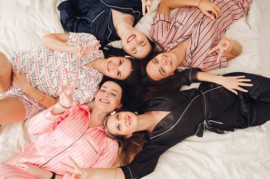 Top view relaxing young girl friends lying on bed having fun posing together