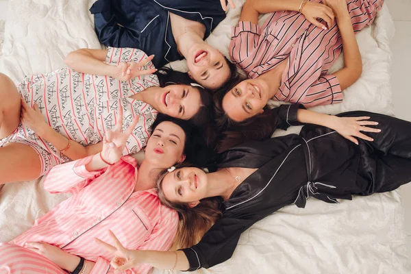 Top view relajantes amigas jóvenes tumbadas en la cama divirtiéndose posando juntas — Foto de Stock