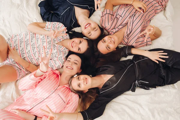 Top view relaxing young girl friends lying on bed having fun posing together — Stok fotoğraf