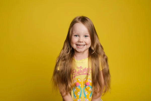 照片中美丽的小女孩，长发笑脸，在黄色的画室背景下显得孤立无援 — 图库照片