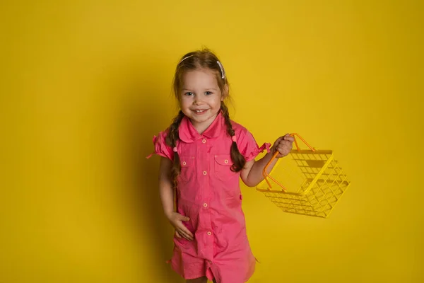 有趣的小女孩与购物篮。黄底分离. — 图库照片