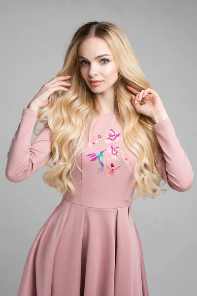 Porträt einer hinreißenden Blondine im rosa Kleid. — Stockfoto