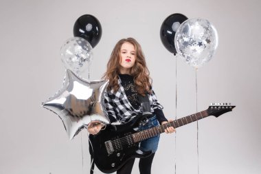 Sevimli bebek rock yıldızı elektro gitar çalıyor ve balonlarla çevrili şarkılar söylüyor.