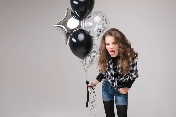 Cooles Pre-Teen Mädchen mit Rock-Zeichen. Sie zeigt Rock n Roll oder Hupzeichen, gestikuliert in die Kamera und schmückt ihre Lippen mit zwei Luftballons. Stock Studio Portrait isoliert auf grau. — Stockfoto