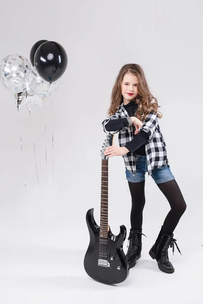 Carino baby girl rock star suonare la chitarra elettrica e cantare canzone circondata da palloncini — Foto Stock