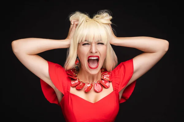 Portrait of screaming fashion blonde woman in red dress holding head having negative emotion Stock Image