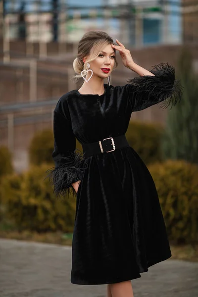 Schöne Frau im eleganten Pelzmantel. Unscharfer Hintergrund. Posieren auf der Straße mit dem Arm vor ihrem Gesicht, wegschauen. — Stockfoto