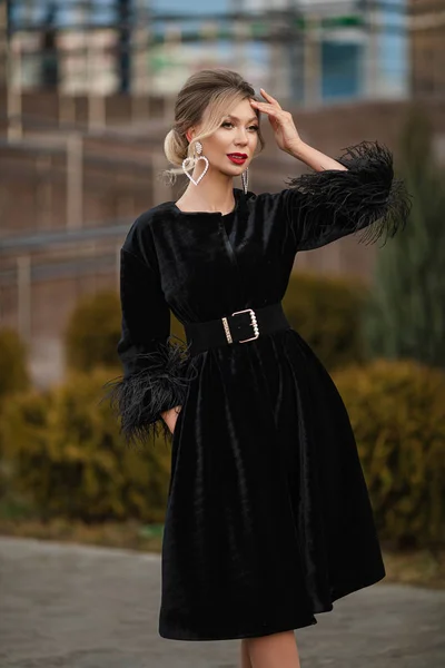 Mulher bonita em casaco de pele elegante. Fundo desfocado. posando na rua com o braço em seu rosto, olhando para longe . — Fotografia de Stock