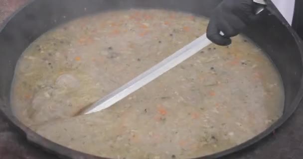 Mixing soup in big cauldron with ladle. — Stock Video