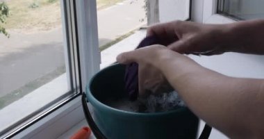 Young lady is cleaning window with detergent