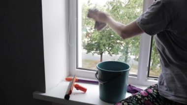 Young lady is cleaning window with detergent