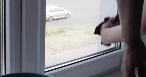Молодая женщина моет окно дома — стоковое видео