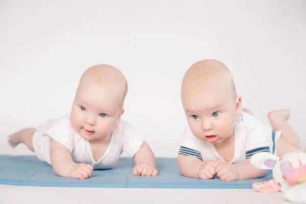 Deux beaux petits bébés couchés sur un lit ensemble et regarde vers la caméra — Photo