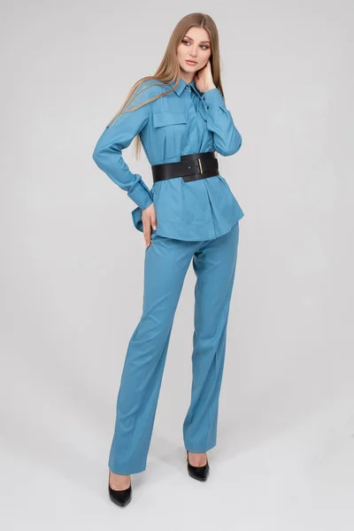 Fashionable young stylish woman posing in blue pantsuit with black belt — Stockfoto