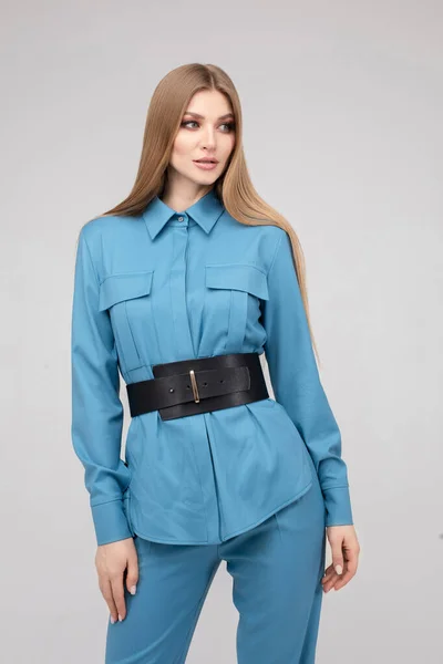 Fashionable young stylish woman posing in blue pantsuit with black belt — Stockfoto