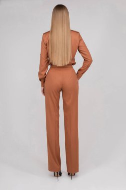 Slim model with long hair in coral jumpsuit.