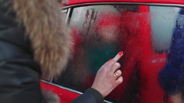 Primer plano femenino dibujo a mano forma de corazón en hielo coche ventana 4k metraje — Vídeos de Stock