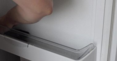 Kadın evdeki buzdolabını yıkıyor.