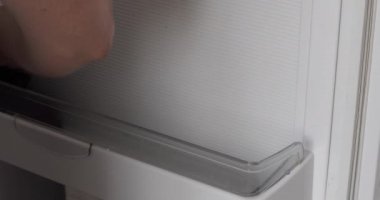 Kadın evdeki buzdolabını yıkıyor.