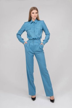 Fashionable pretty lady holding hands in pockets in studio