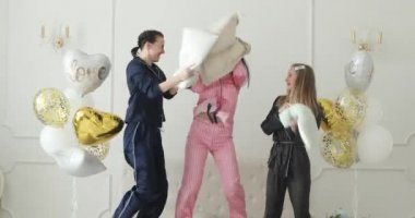 Üç kız arkadaş yastık savaşı yapıyor..