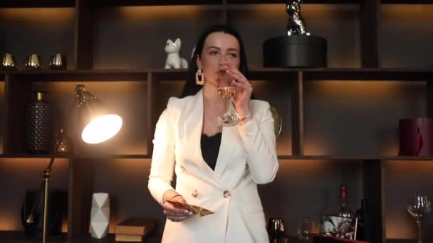 Rijke vrouw drinkt champagne en gooit kaarten naar camera. — Stockvideo