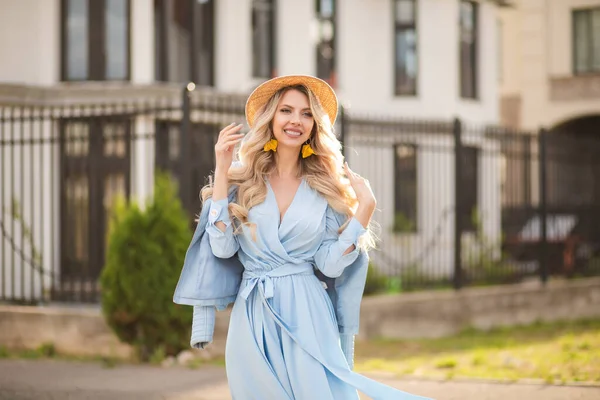 Портрет красивой женщины с длинными светлыми волосами в длинном голубом платье выходит наружу и улыбается — стоковое фото