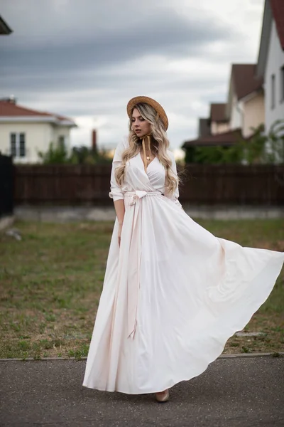 Portrait of beautiful woman with long blonde hair in long white dress walks outside — Stock Photo, Image