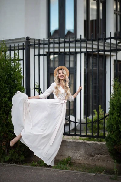 Портрет красивой женщины с длинными светлыми волосами в длинном белом платье выходит наружу — стоковое фото