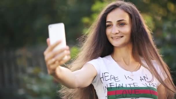 Усміхнена красива дама використовує мобільний телефон у парку — стокове відео