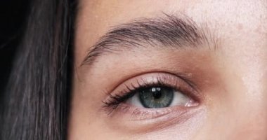 Kadınların gözü yakın planda. Gri yeşil kadın gözü kameraya göz kırpıyor..