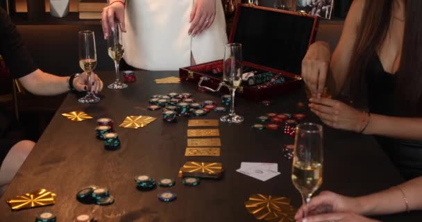 Meninas alegres jogar poker em uma sala com pouca luz e bebe champanhe ou vinho branco de um óculos — Vídeo de Stock