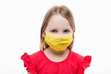Yüzünde sarı tıbbi maske olan, beyaz arka planda izole edilmiş küçük bir kızın portresi.