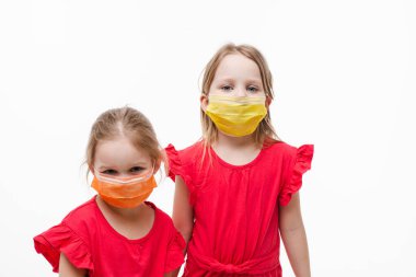 Beyaz stüdyo arka planında izole edilmiş koruyucu tıbbi maske takan iki küçük tatlı kız.