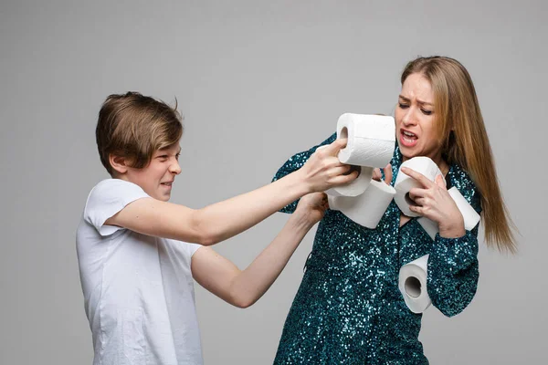 Напружена жінка і панічний хлопець підліток бореться один з одним тримаючи туалет паперові рулони — стокове фото
