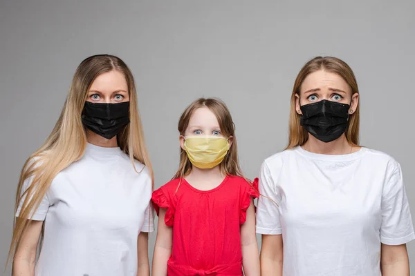 Twee vrouwen en een kind in ademhalingsmaskers. — Stockfoto