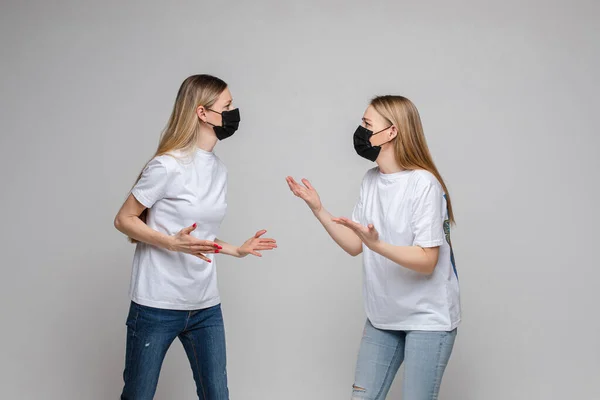 Twee volwassen vrouwen met maskers die ruzie maken. Concept voor de bescherming van het coronavirus. — Stockfoto