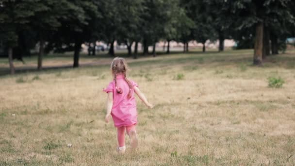 Πορτρέτο του όμορφου μικρού κοριτσιού με μεγάλα μπλε μάτια χαμογελά και τρέχει από την κάμερα — Αρχείο Βίντεο