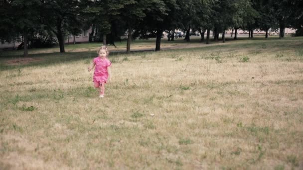Πορτρέτο του όμορφου μικρού κοριτσιού με μεγάλα μπλε μάτια χαμογελά και τρέχει από την κάμερα — Αρχείο Βίντεο