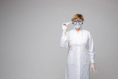 Maskeli doktor stüdyoda termometre tutuyor.