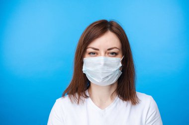 Aseptik maskeli şüpheli bir kadın. açık mavi arkaplan