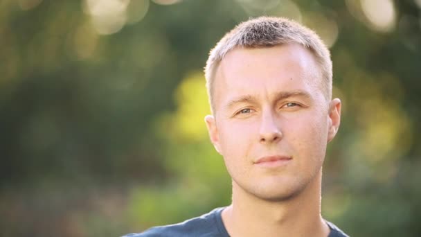 Portrait de joyeux jeune homme posant au parc d'été fond d'arbre vert séquences 4k — Video