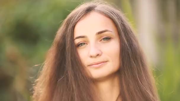 笑顔ブルネット女性タッチ毛の間に一人でポーズで公園 — ストック動画