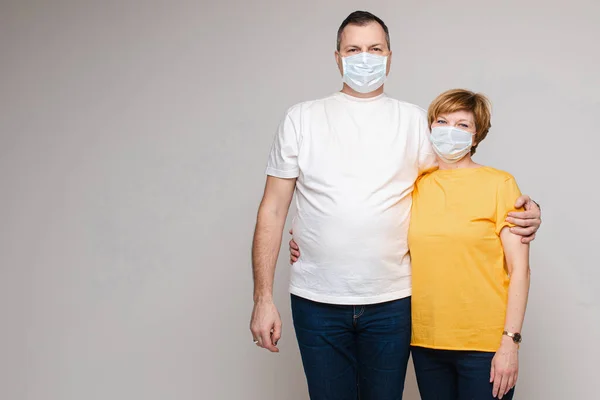 Пара закоханих обіймається разом і стоїть в медичних масках, портрет ізольований на білому тлі — стокове фото