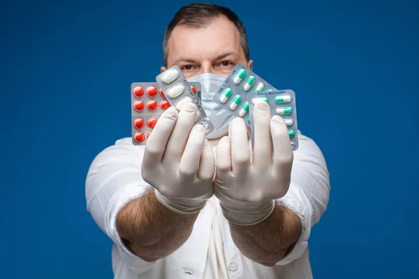 Дорослий чоловік в рукавичках показує таблетки в студії — стокове фото